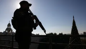 A member of the Palestinian securtiy forces stands guard on a roof overlooking Nativity Square in Bethlehem, in the Israeli-occupied West Bank, ahead of Christmas celebrations on December 24, 2025. (Photo by HAZEM BADER/AFP)