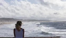 A person looks out over the Pacific Ocean from the Venice Pier during a break in the rain storms affecting Southern California on December 25, 2025 in Venice, California. Torrential rains unleashed flash floods and warnings of debris flow across southern California, particularly in fire-scarred areas, with further downpours forecast for Thursday as authorities declared a state of emergency in several counties. Driven by an atmospheric river known as "the Pineapple Express," which moves heavy moisture from the tropical climes of Hawaii to the US West Coast, the storm was expected to deliver months' worth of rain over a few days. (Photo by Jonathan Alcorn/AFP)