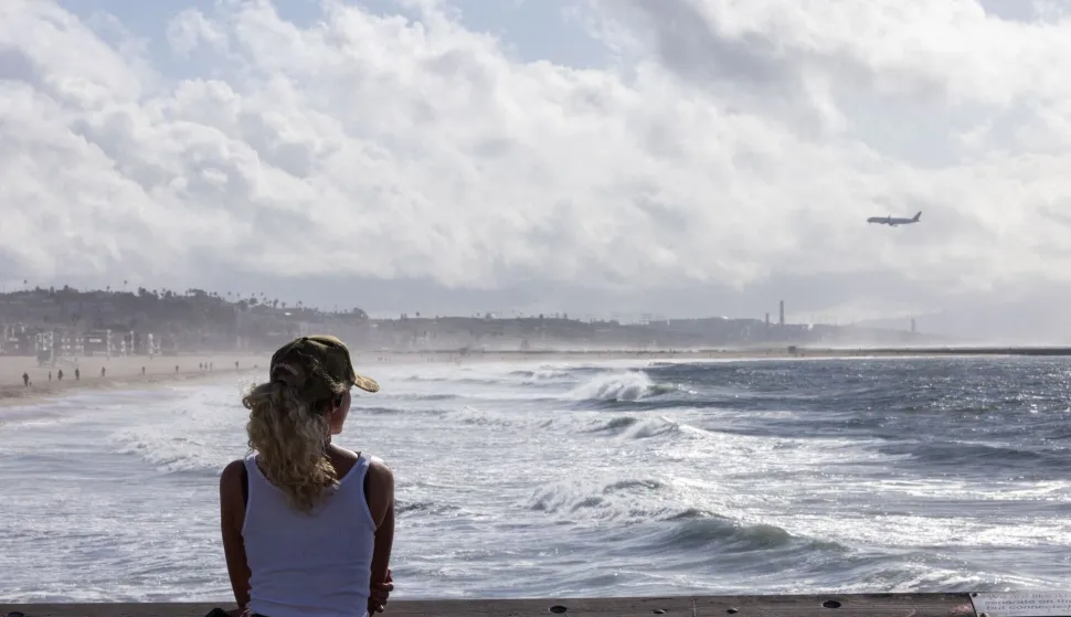 A person looks out over the Pacific Ocean from the Venice Pier during a break in the rain storms affecting Southern California on December 25, 2025 in Venice, California. Torrential rains unleashed flash floods and warnings of debris flow across southern California, particularly in fire-scarred areas, with further downpours forecast for Thursday as authorities declared a state of emergency in several counties. Driven by an atmospheric river known as "the Pineapple Express," which moves heavy moisture from the tropical climes of Hawaii to the US West Coast, the storm was expected to deliver months' worth of rain over a few days. (Photo by Jonathan Alcorn/AFP)