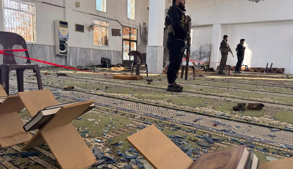 TOPSHOT - Armed men stand inside the Imam Ali ibn Abi Talib Mosque following an explosion in the Wadi al-Dahab neighborhood of Homs on December 26, 2025. A deadly explosion hit a mosque in a predominantly Alawite area of Syria's Homs on December 26, said authorities who reported at least six people killed. "A terrorist explosion targeted the Ali Bin Abi Talib Mosque during Friday prayers in Al-Khadri Street in the Wadi al-Dahab neighbourhood of Homs," the interior ministry said in a statement, adding that six people were killed and 21 others wounded. (Photo by Omar HAJ KADOUR/AFP)