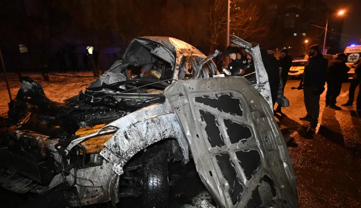 Ukrainian police officers inspect a destroyed car at an impact site following a strike in Kharkiv, on December 26, 2025, amid the Russian invasion of Ukraine. (Photo by SERGEY BOBOK/AFP)