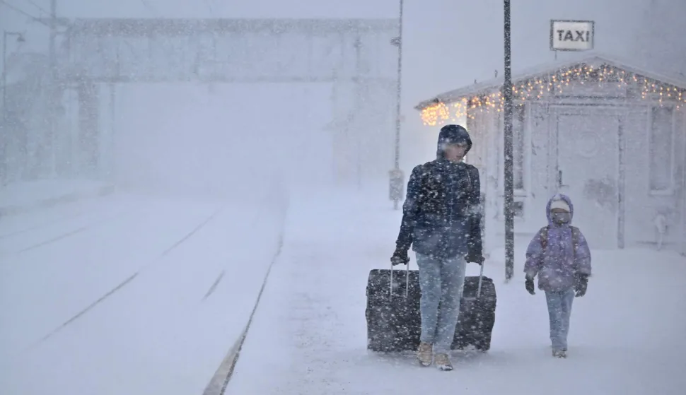 A woman and child make their way with their luggage at the train station in Are as storm Johannes moves in over northern Sweden causing cancelled departures on December 27, 2025. (Photo by Pontus LUNDAHL/various sources/AFP)/Sweden OUT