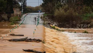 Pedestrians walk next to a flooded road due to the overflowing of the Agly river at the entrance of Rivesaltes in the Pyrenees-Orientales department in south-western France on December 26, 2025. Aude, Pyr?n?es-Orientales and Haute-Corse have been placed on orange alert for rain?flooding or floods by M?t?o-France until midnight on December 26, 2025. (Photo by Jean-Christophe MILHET/AFP)