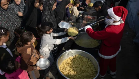epaselect epa12612886 A man wearing a Santa Claus costume takes part in a Hayat Washington Charity initiative to distribute free meals and supplies to displaced Palestinians living in tents in Khan Yunis, southern Gaza Strip, 26 December 2025, amid a ceasefire between Israel and Hamas. EPA/HAITHAM IMAD