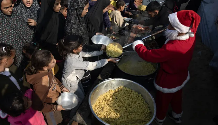 epaselect epa12612886 A man wearing a Santa Claus costume takes part in a Hayat Washington Charity initiative to distribute free meals and supplies to displaced Palestinians living in tents in Khan Yunis, southern Gaza Strip, 26 December 2025, amid a ceasefire between Israel and Hamas. EPA/HAITHAM IMAD