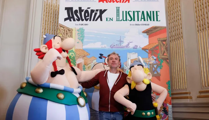 (FILES) French writer Fabrice Caro better known as Fabcaro poses for photographs alongside performers in Asterix (R) and Obelix (L) costumes, during a presentation of the 41st edition of French comic book series "Asterix le Gaulois", titled "Asterix en Lusitanie" (Asterix in Lusitania), illustrated by Didier Conrad and written by Fabcaro, during a press conference held at the Portuguese Embassy in Paris, on October 13, 2025. The latest Asterix album, "Asterix in Lusitania," has sold 1.65 million copies since its release on October 23, making it the best launch for the famous comic in 20 years, the publisher said December 31, 2025. (Photo by Ian LANGSDON/AFP)