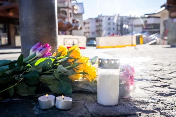 A photograph taken on January 1, 2026 shows flowers and candles laid on the ground near the bar Le Constellation following a fire that ripped through the venue in Crans-Montana, during New Year's Eve celebrations. Several dozen people are presumed dead and around 100 injured after a fire ripped through a crowded bar in the luxury Swiss ski resort town of Crans-Montana, police said early January 1, 2026. (Photo by MAXIME SCHMID/AFP)