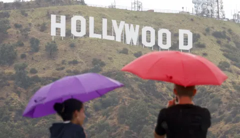 epa10811052 People look out at the Hollywood Sign in the rain nearby Lake Hollywood Park in Los Angeles, California, USA, 20 August 2023. Southern California is under a tropical storm warning as Hilary makes landfall. The last time a tropical storm made landfall in Southern California was 15 September 1939, according to the National Weather Service. EPA/CAROLINE BREHMAN