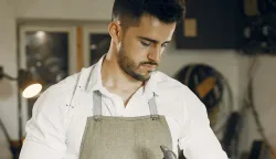 Man working with a wood. Carpenter in a white shirt. Man with a chisel and a hammer