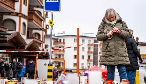 A mourner lights a candle near the bar Le Constellation where a fire ripped through the venue during New Year's celebrations in the Alpine ski resort town of Crans-Montana killing around 40 people and injuring more than 100 others, in Crans-Montana on January 2, 2026. Investigators raced on January 2, 2026 to identify the victims of a fire that ripped through a bar in the Swiss Alps town of Crans-Montana, turning a New Year's celebration into one of the country's worst tragedies. Frederic Gisler, police commander in the Wallis canton in southwestern Switzerland, told reporters that authorities had counted "around 40 people who have died and around 115 injured, most of them seriously". (Photo by MAXIME SCHMID/AFP)