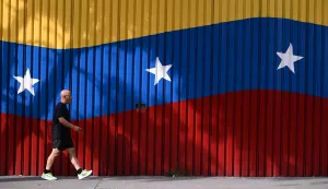 A man walks past a mural with the colors of the Venezuelan flag, after U.S. President Donald Trump said on Saturday that the airspace above and around Venezuela would be completely closed, amid rising tensions between the Trump administration and the government of Venezuelan President Nicolas Maduro, in Caracas, Venezuela, November 29, 2025. REUTERS/Gaby Oraa Photo: GABY ORAA/REUTERS