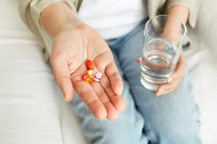 Pills, tablets, vitamins and drugs heap in mature hands, closeup view.