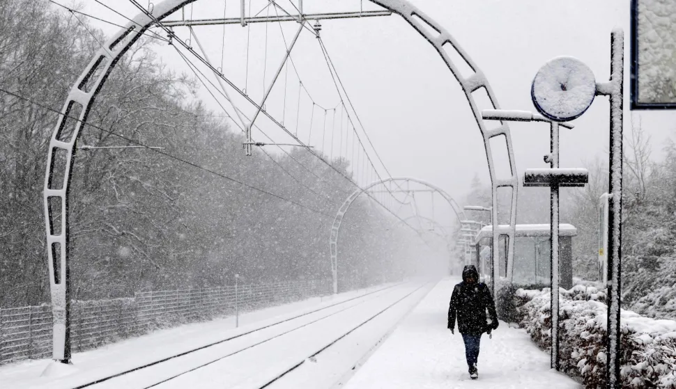 A train passenger walks on a snow-covered platform along a railway in Hollandsche Rading, The Netherlands on January 5, 2026 as train traffic is affected by the wintry weather. (Photo by Sander Koning/ANP/AFP)/Netherlands OUT