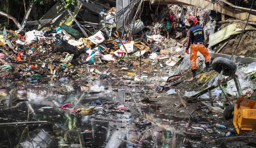 Members of the search and rescue team look for people after a landslide at the landfill in Barangay Binaliw, Cebu City on January 11, 2026. Hard hat-wearing rescue workers and backhoes dug through rubble in search of survivors on January 10 in the shadow of a mountain of garbage that buried dozens of landfill employees in the central Philippines, killing at least six. (Photo by Cheryl Baldicantos/AFP)