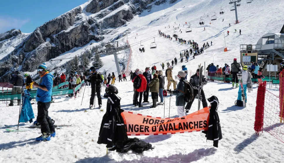 (FILES) Skiers queue for the lift near a sign warning of avalanche risk during the re-opening of the ski resort at Col de la Balme in La Clusaz, French Alps on May 23, 2021 as the country loosened Covid-19 restrictions. Two avalanches killed two skiers in the French Alps on January 11, 2026, resort officials said, following the deaths of three off-piste skiers a day earlier in similar incidents. In one incident, a British skier aged about 50 was buried while skiing off-trail, according to a statement released by La Plagne ski resort in southeastern France. (Photo by Olivier CHASSIGNOLE/AFP)
