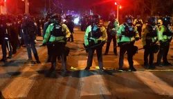 State troopers form a line in the street in Minneapolis, Minnesota, on January 14, 2026, after protesters clashed with federal law enforcement following the shooting of a Venezuelan man by a Immigration and Customs Enforcement (ICE) agent. A federal immigration agent shot a man January 14 in Minneapolis, city officials said, urging the public to "remain calm" a week after agents shot and killed an American woman in the same city.Minneapolis Police Chief Brian O'Hara said the shooting resulted from a struggle in front of a residence between a man and an Immigration and Customs Enforcement (ICE) agent on the north side of the city. (Photo by Octavio JONES/AFP)