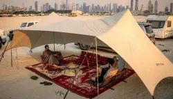 AFP PICTURES OF THE YEAR 2025People sit in the shade of a tent near camper vehicles parked by a backdrop of the Dubai skyline including Burj Khalifah, the world's tallest structure, on January 31, 2025. (Photo by FADEL SENNA/AFP)/AFP PICTURES OF THE YEAR 2025