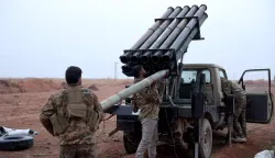 Syrian government forces load a rocket to launch towards Kurdish forces near Dibsi Faraj in the northern Syrian Tabqa area, on January 17, 2026. Syria's army took control of swathes of northern Syria and threatened to bomb parts of Raqa province on January 17, after Kurdish forces pulled back from territory they had held for over a decade. The government appeared to be seeking to extend its grip on parts of the country under Kurdish control a day after President Ahmed al-Sharaa issued a decree declaring Kurdish a "national language" and granting the minority official recognition. (Photo by OMAR HAJ KADOUR/AFP)