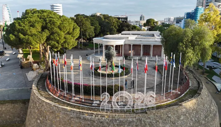 This aerial picture shows flags of EU member states adorning a section of the Venetian Walls of the divided capital Nicosia, on the grounds of the old municipal palace at Eleftheria Square on January 2, 2026. The Republic of Cyprus will hold the Presidency of the Council of the European Union for the first half of 2026. (Photo by Etienne TORBEY/AFP)