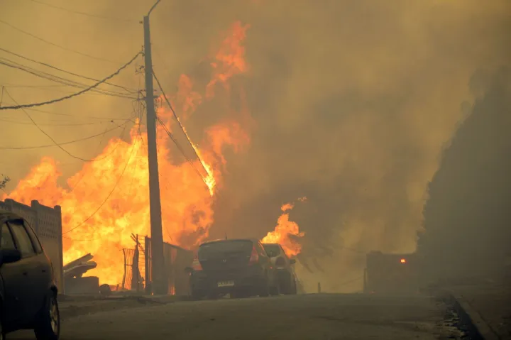 TOPSHOT - Smoke and flames billow from a burning house and a vechicle during a wildfire in Concepcion, Chile, on January 18, 2026. Chilean President Gabriel Boric declared a state of emergency on January 18 for two southern regions where raging wildfires have forced about 20,000 people to evacuate their homes. (Photo by GUILLERMO SALGADO/AFP)