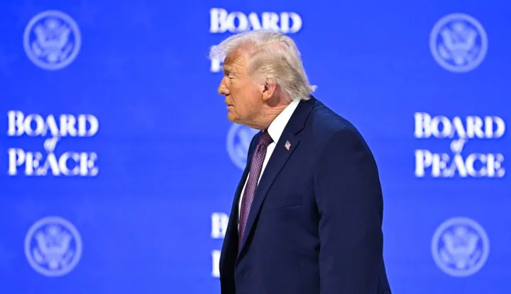 TOPSHOT - US President Donald Trump walks at the "Board of Peace" meeting during the World Economic Forum (WEF) annual meeting in Davos on January 22, 2026. US President Donald Trump will show off his new "Board of Peace" at Davos on January 22, 2026 burnishing his claim to be a peacemaker a day after backing off his own threats against Greenland. Originally meant to oversee the rebuilding of Gaza after the war between Hamas and Israel, the board's charter does not limit its role to the Strip, and has sparked concerns that Trump wants it to rival the United Nations. (Photo by Fabrice COFFRINI/AFP)
