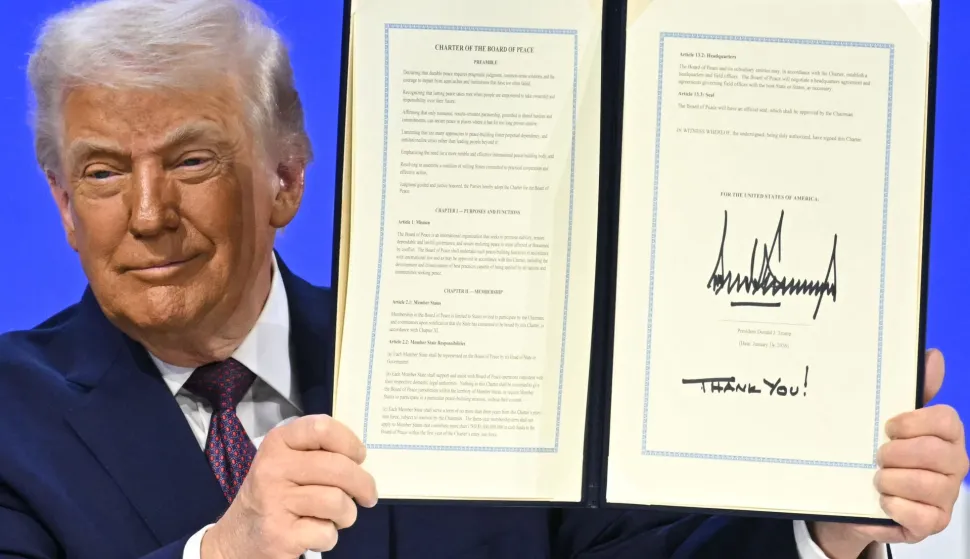 TOPSHOT - US President Donald Trump holds a signed founding charter at the "Board of Peace" meeting during the World Economic Forum (WEF) annual meeting in Davos on January 22, 2026. US President Donald Trump will show off his new "Board of Peace" at Davos on January 22, 2026 burnishing his claim to be a peacemaker a day after backing off his own threats against Greenland. Originally meant to oversee the rebuilding of Gaza after the war between Hamas and Israel, the board's charter does not limit its role to the Strip, and has sparked concerns that Trump wants it to rival the United Nations. (Photo by Fabrice COFFRINI/AFP)
