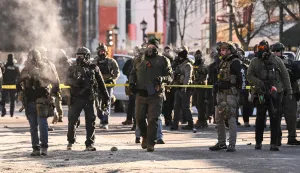 Federal agents stand near police tape as demonstators gather near the site of where state and local authorities say a man was shot by federal agents earlier in the morning in Minneapolis, Minnesota, on January 24, 2026. Minnesota Governor Tim Walz said Saturday that federal agents deployed in Minneapolis as part of a sweeping immigration crackdown had carried out "another horrific shooting," less than three weeks after the fatal shooting of Renee Good. (Photo by ROBERTO SCHMIDT/AFP)