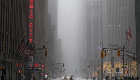 A man walks across Sixth Avenue as snow falls in the Manhattan borough of New York City on January 25, 2026. A massive winter storm on January 24 dumped snow and freezing rain from New Mexico to North Carolina as it swept across the United States towards the northeast, threatening tens of millions of Americans with blackouts, transportation chaos and bone-chilling cold. After battering the country's southwest and central areas, the storm system began to hit the heavily populated mid-Atlantic and northeastern states as a frigid air mass settled in across the nation. (Photo by CHARLY TRIBALLEAU/AFP)