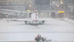 TOPSHOT - A snow removal machine is seen working on the tarmac of LaGuardia airport in New York on January 25, 2026. A massive winter storm on January 24, 2026 dumped snow and freezing rain on New Mexico and Texas as it swept across the United States towards the northeast, threatening tens of millions of Americans with blackouts, transportation chaos and bone-chilling cold. Shoppers stripped supermarket shelves as the National Weather Service (NWS) forecast huge snowfall in some areas and possibly "catastrophic" ice accumulations. (Photo by CHARLY TRIBALLEAU/AFP)