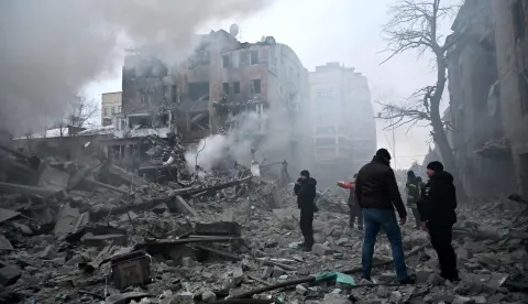 Local residents stand next to damaged residential buildings following a Russian air strike in Kharkiv on January 2, 2026, amid the Russian invasion of Ukraine. (Photo by SERGEY BOBOK/AFP)
