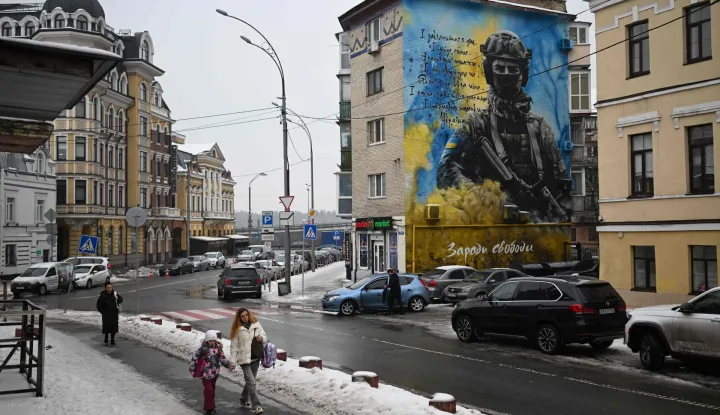 Pedestrians walk past a residential building with a patriotic mural depicting a Ukrainian soldier in Kyiv on January 28, 2026, amid the Russian invasion of Ukraine. (Photo by Sergei GAPON/AFP)