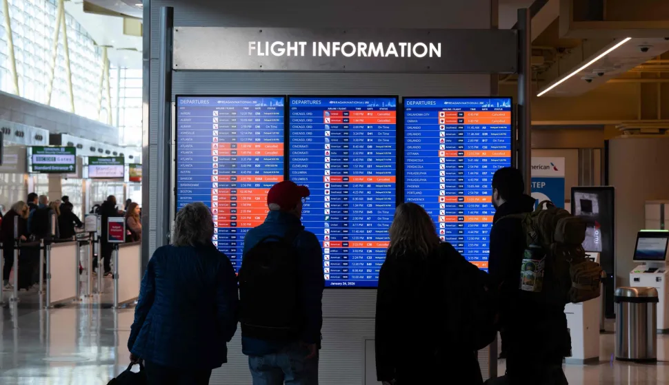Travelers look at a flight status board as flights are delayed and cancelled following a significant winter storm at Ronald Reagan Washington National Airport in Arlington, Virginia, January 26, 2026. Millions of Americans were facing dangerously cold temperatures in the wake of a massive winter storm that whipped snow and ice across the country, knocking out power and paralyzing transportation. A frigid, potentially life-threatening Arctic air mass threatened to delay clean-up as municipalities from New Mexico to Maine tried to dig out following the storm, which dropped a vicious cocktail of heavy snow and wind along with freezing rain and sleet. (Photo by SAUL LOEB/AFP)