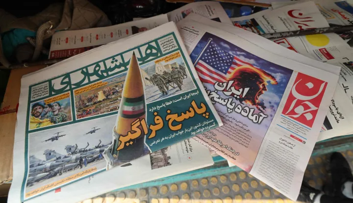 A photograph shows newspapers, one of them (R) with a headline in Persian reading ?Iran is ready for a big response?, at a kiosk in Tehran on January 27, 2026. A US naval strike group led by an aircraft carrier has deployed to Middle Eastern waters, the United States said on January 26, 2026, as Tehran warned it was ready to hit back at any American attack launched in response to a crackdown on anti-government protests. (Photo by ATTA KENARE/AFP)