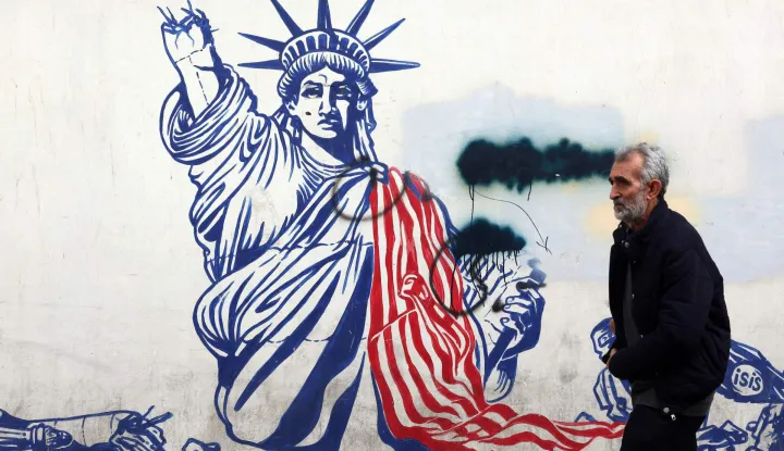 A man walks past a mural depicting the US Statue of Liberty with the torch-bearing arm broken, painted on the outer walls of the former US embassy, in Tehran on February 6, 2026. Iran's Foreign Minister met with his Omani counterpart in Muscat on February 6, ahead of Oman-mediated talks with the United States on the Islamic republic's nuclear programme. (Photo by AFP)
