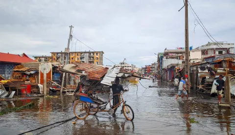 TOPSHOT - A man pushes a bycicle through a flooded street in the city of Toamasina, on the east coast of Madagascar, struck by Tropical Cyclone Gezani on February 11, 2026. (Photo by Tsiky Sikonina/AFP)