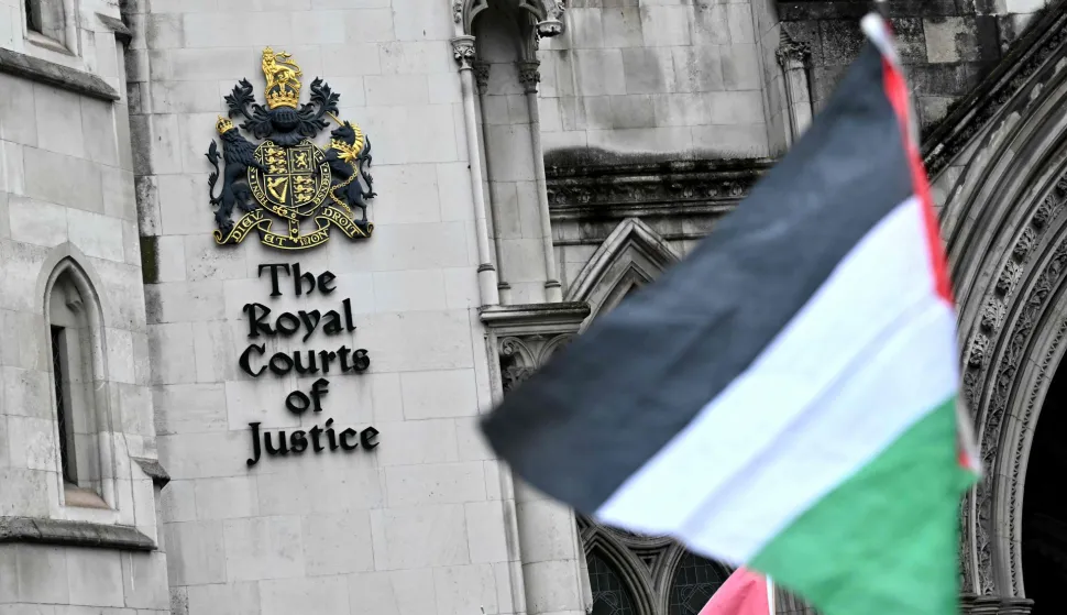 A Palestinian flag is flown by a protestor outside The Royal Courts of Justice, Britain's High Court, in London on February 13, 2026. Palestine Action co-founder Huda Ammori is set Friday to learn the outcome of his challenge against the UK Government's ban on the group, which came into force in July 2025, after pro-Palestine activists protesting the war in Gaza, broke into a UK air force base and caused an estimated ?7 million ($9.3 million) of damage. (Photo by Ben STANSALL/AFP)