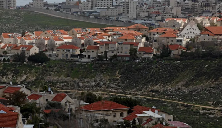 Israel's controversial barrier is pictured separating the Israeli settlement of Pisgat Zeev (foreground), built in a suburb of the predominantly-Arab and Israeli-annexed East Jerusalem, and the Palestinian village of Anata (background) on February 11, 2026. (Photo by AHMAD GHARABLI/AFP)