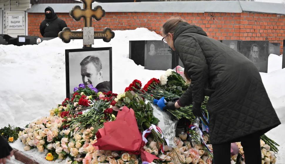 A woman lays flowers at the grave of Russian opposition leader Alexei Navalny at the Borisovo cemetery in Moscow on February 16, 2026, marking the second anniversary of his death in an Arctic colony. (Photo by Hector RETAMAL/AFP)/NAVALNY HAS BEEN DECLARED "EXTREMIST" BY RUSSIAN AUTHORITIES. IN RUSSIA, ANYBODY WHO MENTIONS NAVALNY OR HIS ANTI-CORRUPTION FOUNDATION WITHOUT STATING THAT THEY HAVE BEEN DECLARED "EXTREMIST" IS SUBJECT TO FINES OR UP TO FOUR YEARS IN PRISON FOR REPEATED OFFENCES./