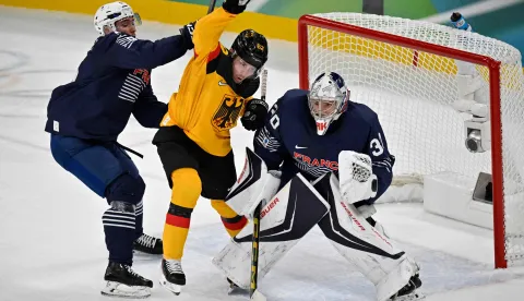 France's #05 Enzo Guebey (L) and France's #30 Antoine Keller (R) vie with Germany's #62 Parker Tuomie during the men's qualification play-off ice hockey match between Germany and France at the Milano Santagiulia Ice Hockey Arena during the Milano Cortina 2026 Winter Olympic Games in Milan, on February 17, 2026. (Photo by Alexander NEMENOV/AFP)