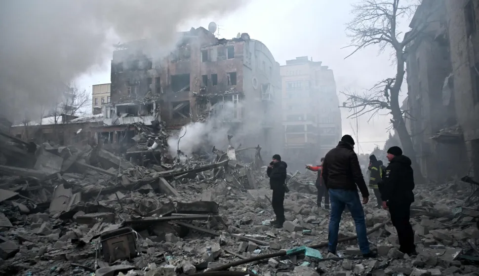 Local residents stand next to damaged residential buildings following a Russian air strike in Kharkiv on January 2, 2026, amid the Russian invasion of Ukraine. (Photo by SERGEY BOBOK/AFP)