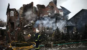 TOPSHOT - A Ukrainian rescuer stands next to a heavily damaged house following an air attack in Sofiivska Borshchagivka, Kyiv region on February 22, 2026, amid the Russian invasion of Ukraine. Explosions rocked Ukraine's capital Kyiv with officials warning of a ballistic missile attack, just two days before the fourth anniversary of Russia's invasion. (Photo by Henry NICHOLLS/AFP)