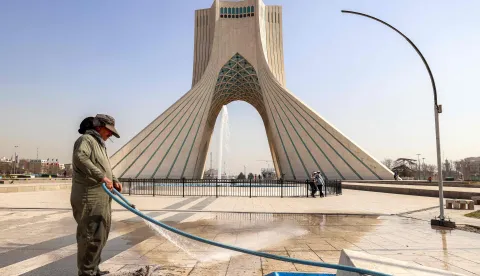A municipal worker uses a hose to clean an area of Azadi (Freedom) Square near the landmark Azadi Tower in Tehran on February 23, 2026. The 45-metre-tall marble-clad Azadi Tower, formerly known as Shahyad Tower (Shah's Memorial Tower'), was commissioned by Mohammad Reza Pahlavi, the last Shah of Iran, to mark the 2,500-year celebration of the Persian Empire, and completed in 1971. It was erected at the westernmost entrance to the city of Tehran. (Photo by ATTA KENARE/AFP)
