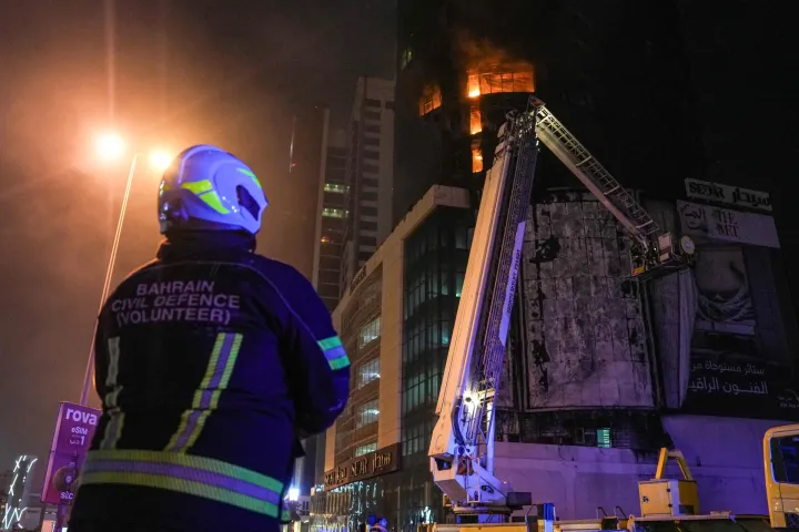 TOPSHOT - Emergency personnel work to extinguish a fire in a building after an Iranian strike in the capital Manama on February 28, 2026. The United States and Israel launched waves of strikes on February 28 against targets in Iran, sparking swift retaliation by the Islamic republic which responded with missile attacks across the region. (Photo by Fadhel MADAN/AFP)