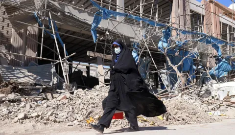 A woman walks past a heavily-damaged building near Ferdowsi square in Tehran on March 3, 2026. The United States and Israel started striking Iran on February 28, killing Iran's supreme leader and top military leaders, and prompting authorities to retaliate with strikes on Israel and across the Gulf. (Photo by ATTA KENARE/AFP)