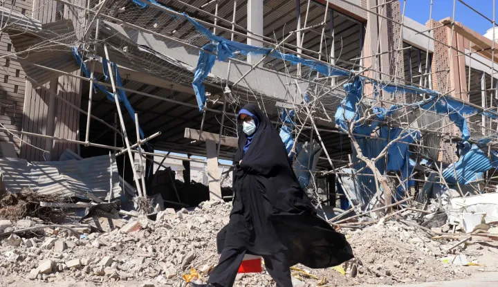 A woman walks past a heavily-damaged building near Ferdowsi square in Tehran on March 3, 2026. The United States and Israel started striking Iran on February 28, killing Iran's supreme leader and top military leaders, and prompting authorities to retaliate with strikes on Israel and across the Gulf. (Photo by ATTA KENARE/AFP)
