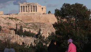 epa09663678 Two people sit on a wall overlooking the Temple of Athena Nike at the Acropolis in Athens, Greece, 02 January 2022. EPA/GEORGE VITSARAS