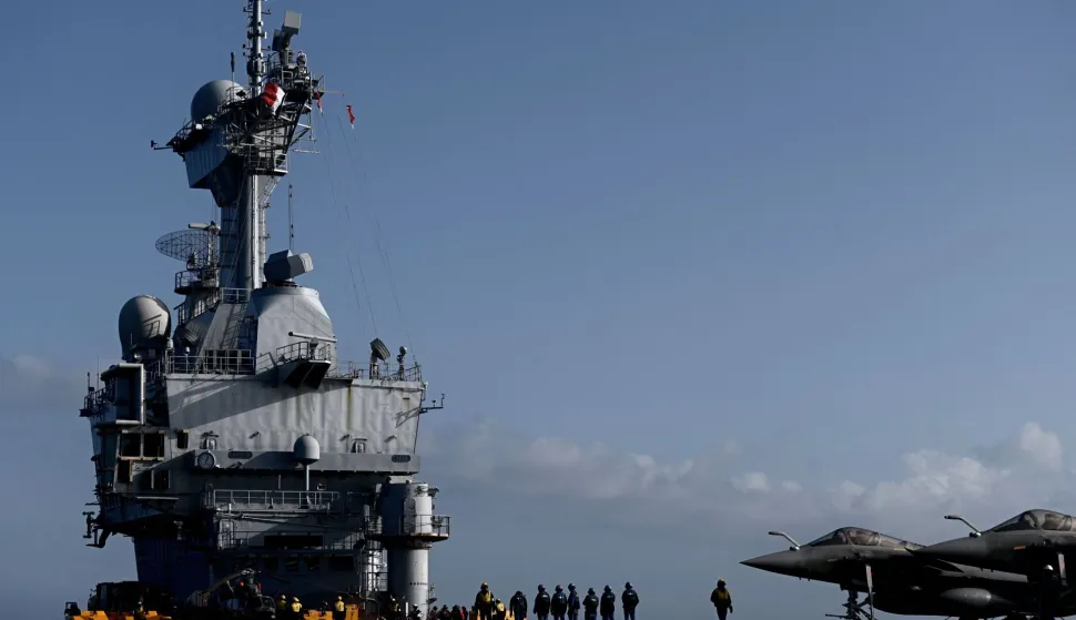 (FILES) Military staff stand past Rafale jet fighters on the deck of the French aircraft carrier Charles de Gaulle at sea, off the coast of the city of Hyeres on January 23, 2020. Emmanuel Macron announced on March 3, 2026 additional military reinforcements to the war-torn Middle East, including the aircraft carrier Charles de Gaulle and its escort of frigates, which will ?set course? for the Mediterranean. (Photo by Philippe LOPEZ/POOL/AFP)