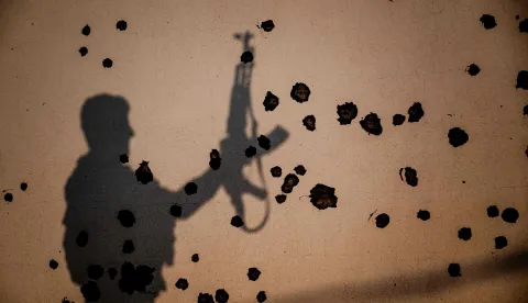 TOPSHOT - The shadow of a Kurdish fighter, a member of The Organization of Iranian Kurdistan Struggle (Sazmani Khabat), falls on the shrapnel scarred wall of a damaged building, following an Iranian drone attack to their base near Erbil, in Iraq's northern autonomous Kurdish region on March 9, 2026. Iran has designated Kurdish rebels groups as terrorist organisations, and many have previously fought its security forces in Kurdish-majority areas along the border. (Photo by Ozan KOSE/AFP)