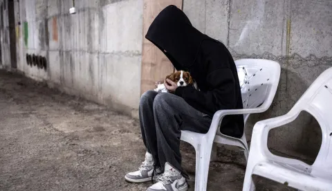 TOPSHOT - A man holds tight on his dog in an underground parking used as a bomb shelter during an alert in Tel Aviv on March 12, 2026. Lebanon's Hezbollah said it launched missiles at an Israeli military intelligence base in the suburbs of Tel Aviv early on March 12, the Iran-backed group's latest claim in a major operation against Israel it announced hours earlier. (Photo by OLYMPIA DE MAISMONT/AFP)/