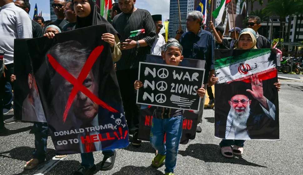Children hold placards showing US President Donald Trump (L) and Iran's slain supreme leader Ayatollah Ali Khamenei (R) during a demonstration to mark al-Quds (Jerusalem) Day, after Friday prayers in Kuala Lumpur on March 13, 2026. (Photo by Mohd Rasfan/AFP)